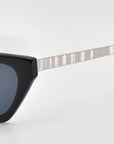 Close-up of For Art's Sake® Mesa II sunglasses with a thick, glossy acetate frame and a silver, textured metal arm against a plain white background.