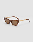 The For Art’s Sake® Mesa II sunglasses feature a brown cat-eye shape, gold-accented temples, a patterned acetate frame, and tinted lenses, showcased against a plain light gray background.