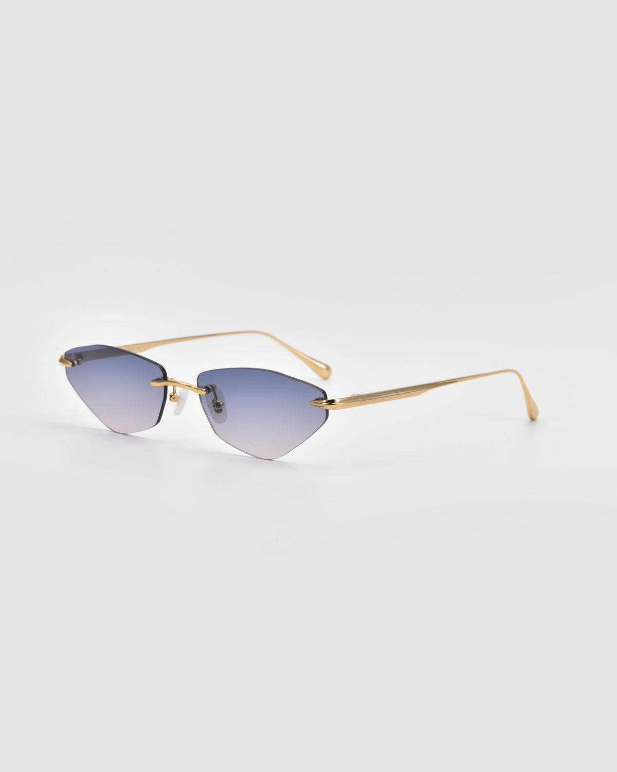 For Art’s Sake® Sienna I sunglasses showcase a rimless design with gradient blue lenses, slender gold metal arms, and jade stone nose pads, presented gracefully against a light gray backdrop.