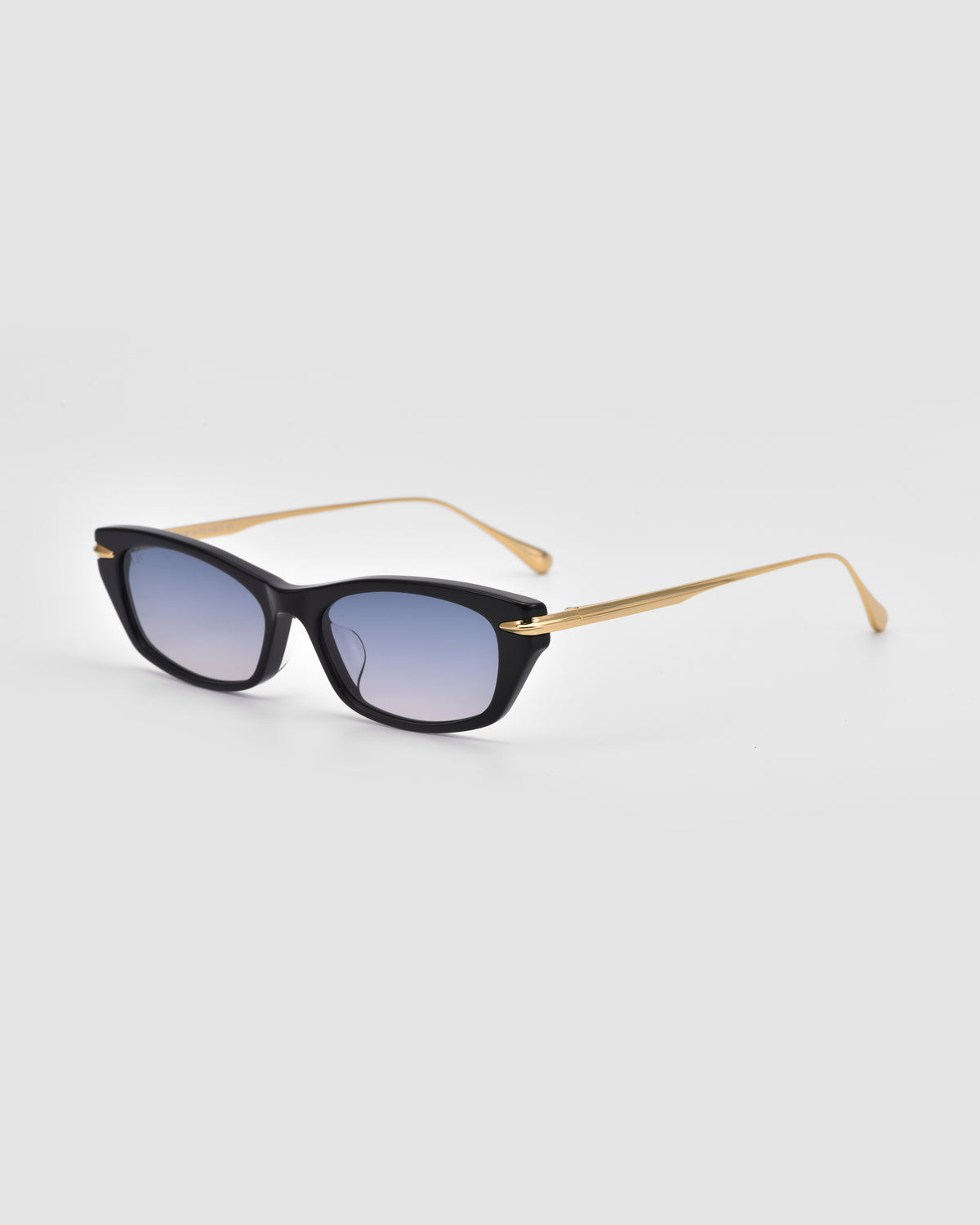 The Marisol I by For Art’s Sake® features black rectangular sunglasses with gold arms and blue-tinted lenses, crafted from sleek acetate and displayed on a plain light background.