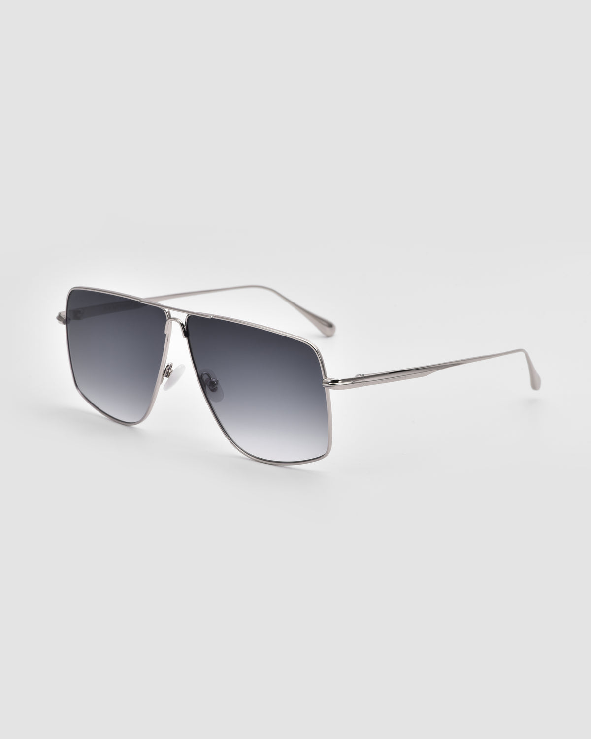 The Marisol II by For Art’s Sake® features oversized aviator sunglasses with thin metal frames, sculpted accents, and dark gradient lenses, shown on a light gray background.