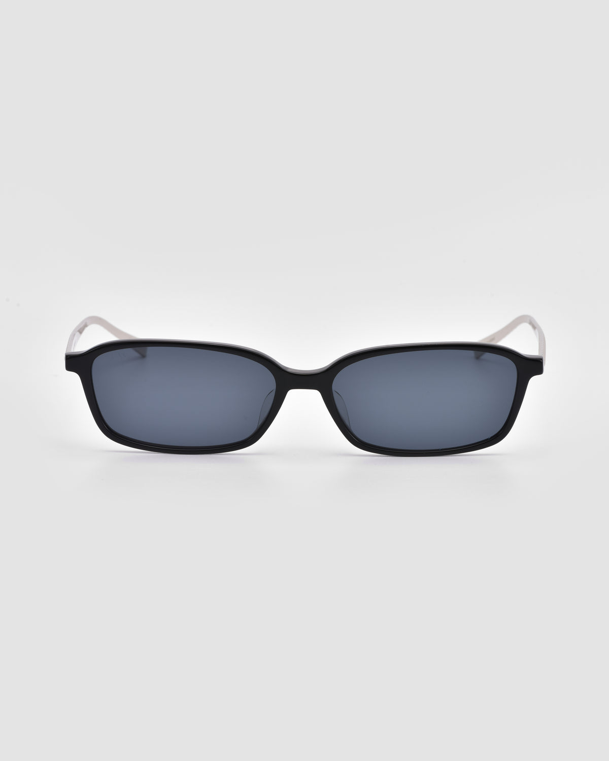 The Solana I by For Art’s Sake®: rectangular black sunglasses with dark lenses and white arms, shown front view on a white background—modern style designed for lightweight comfort.