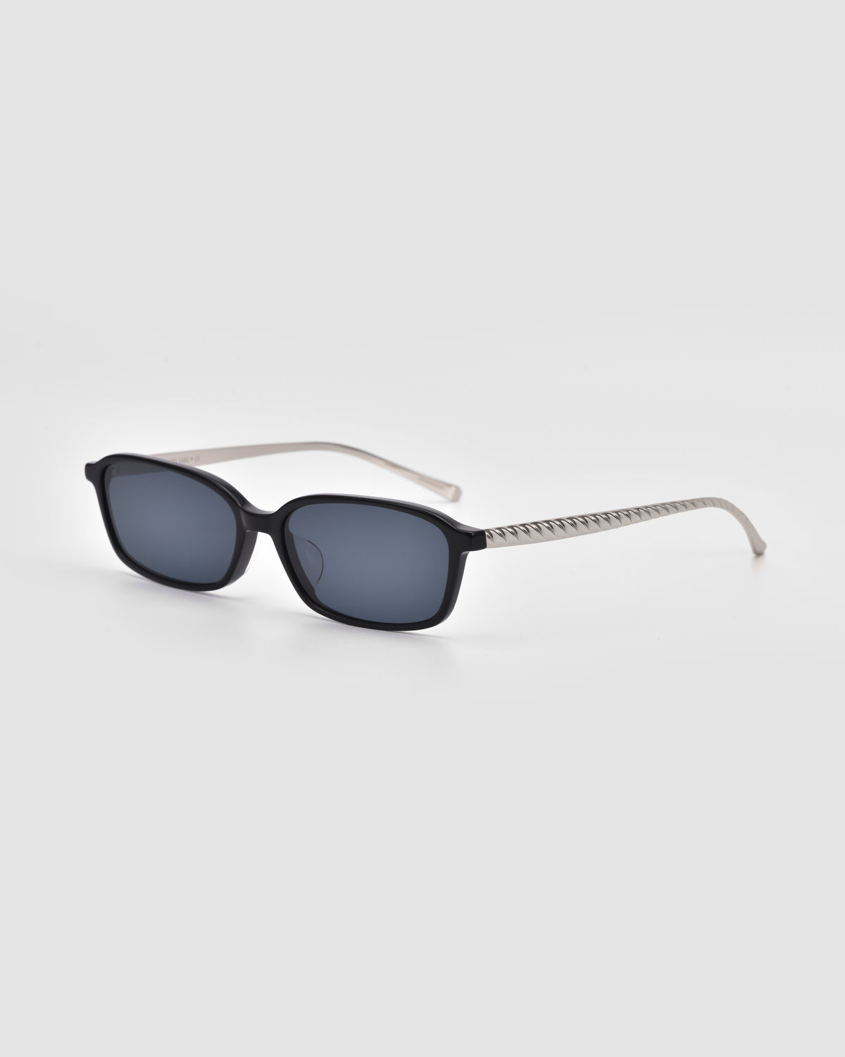 Solana I by For Art’s Sake® are rectangular black modern sunglasses with dark lenses and striped, light-colored arms—statement eyewear combining style and lightweight comfort, shown on a plain light gray background.