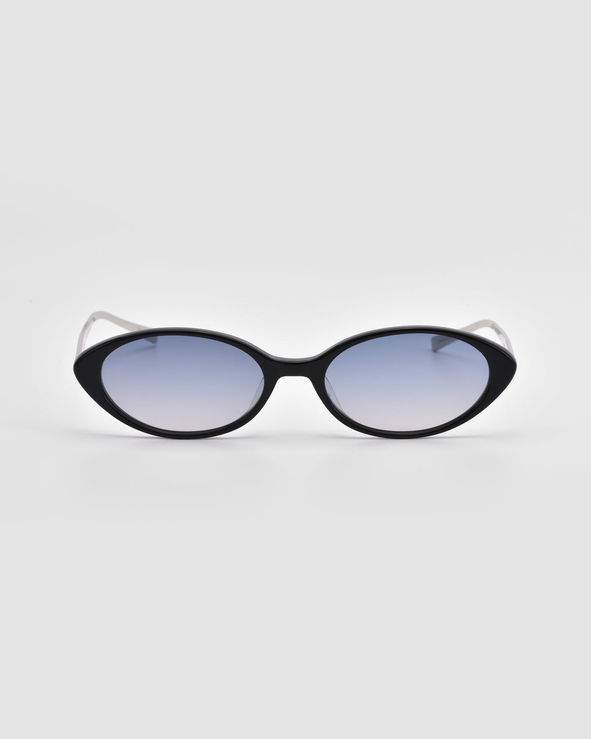 Solana II by For Art’s Sake® are black oval acetate sunglasses with dark gradient lenses, shown on a light gray background.