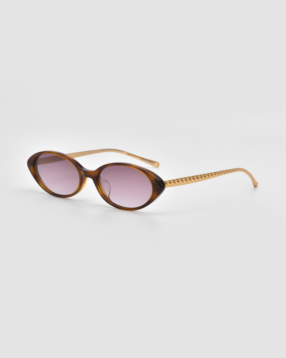 Solana II by For Art’s Sake®: Oval brown tortoiseshell statement eyewear with purple tinted lenses and gold-toned arms, displayed on a light gray background.