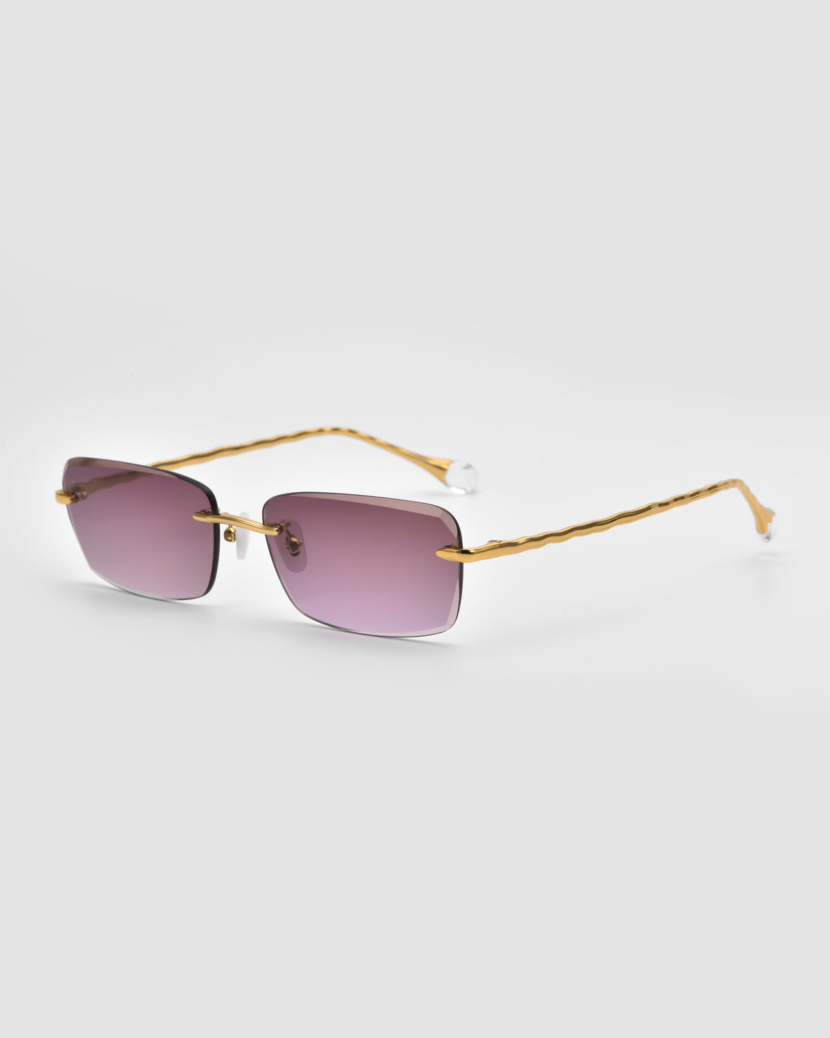 Sol I by For Art’s Sake®: rectangular translucent Jewel sunglasses with purple lenses, thin gold wavy arms, and sculpted nylon tips from the Sol State collection, shown on a plain white background.