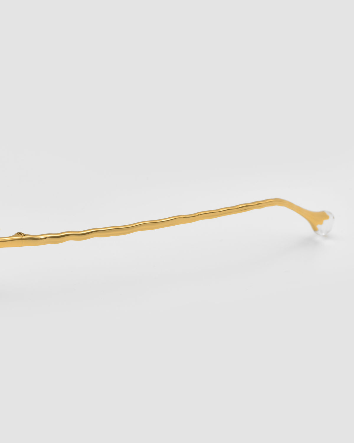 Close-up of a gold eyeglass arm with a wavy design from the Sol II by For Art’s Sake®, shown on a plain white background.