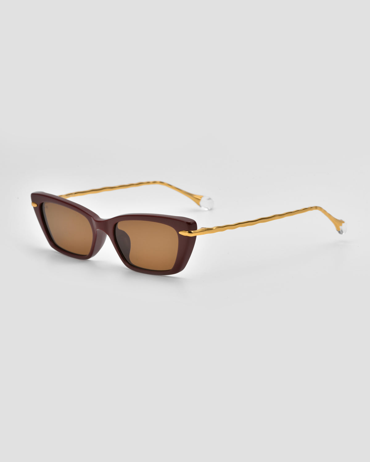 The Sol II by For Art’s Sake® from the Sol State collection features dark brown frames, gold wavy metal arms with jewel-like clear accents, and brown-tinted lenses.