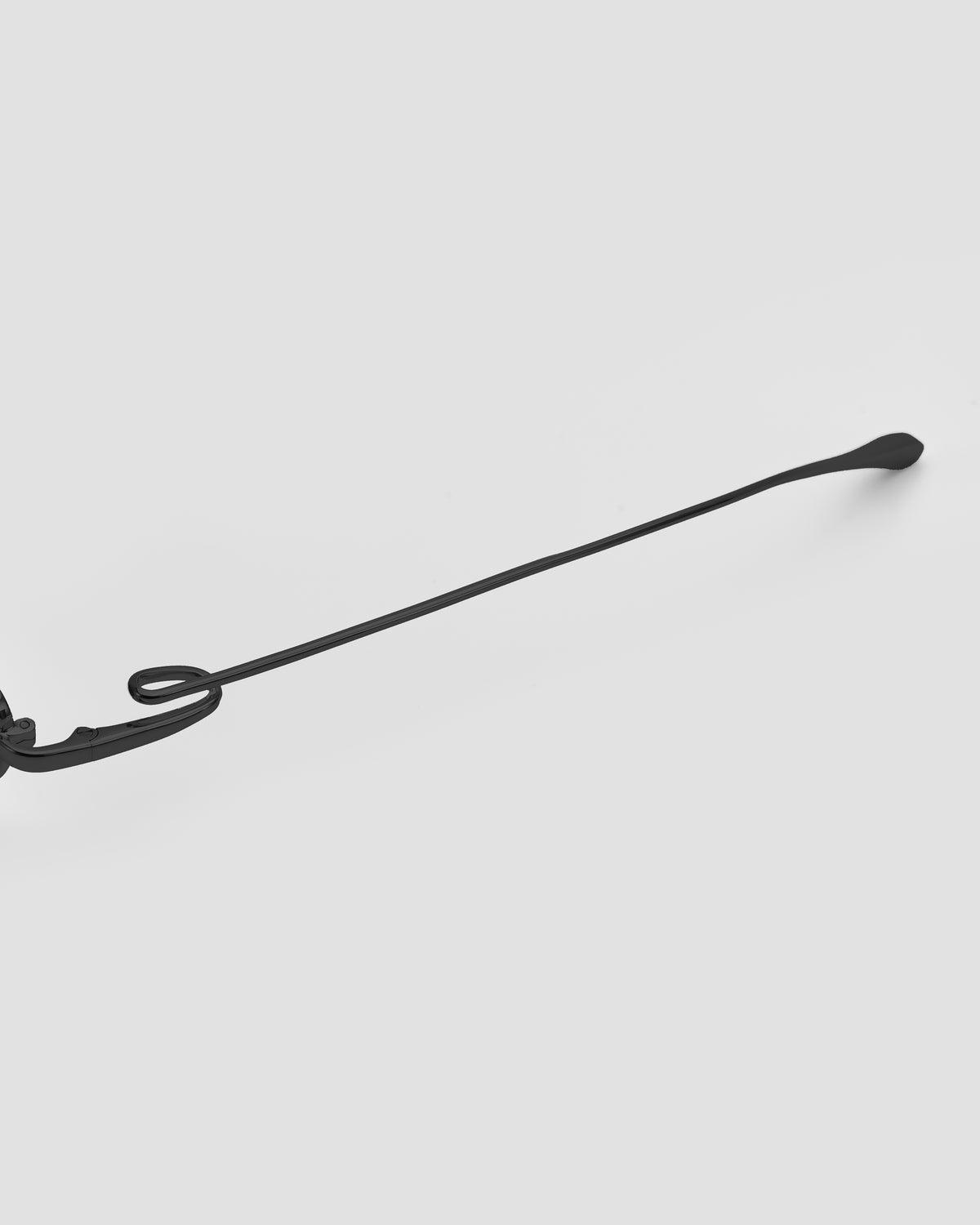 Ozanne I by For Art’s Sake®: a single black metal piece with a curved hook and flat, rounded tip, inspired by jewellery eyewear, set against a plain light gray background.