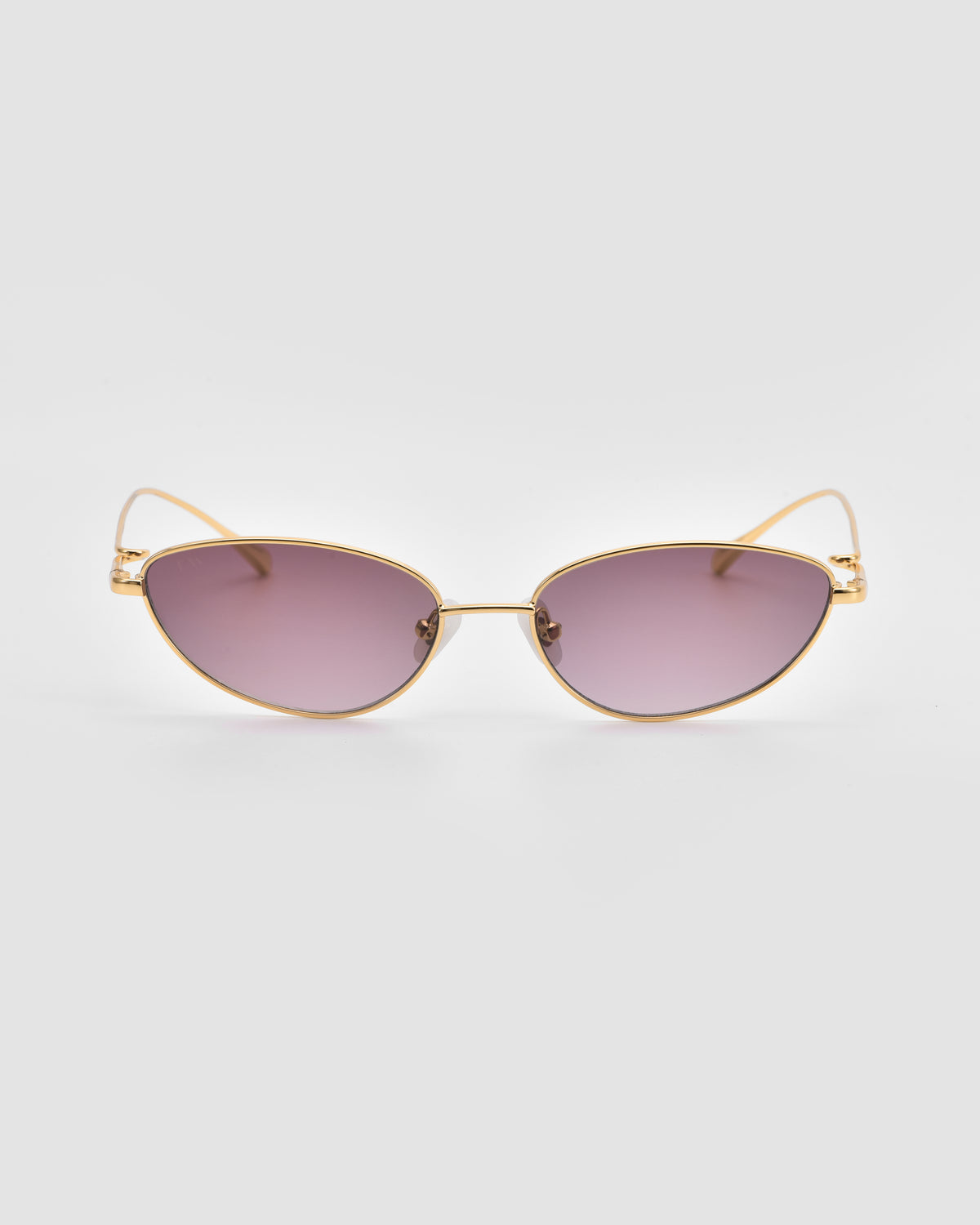 Ozanne I by For Art’s Sake®: Cat-eye sculptural sunglasses with gold frames and purple-tinted lenses, shown against a plain light gray background.