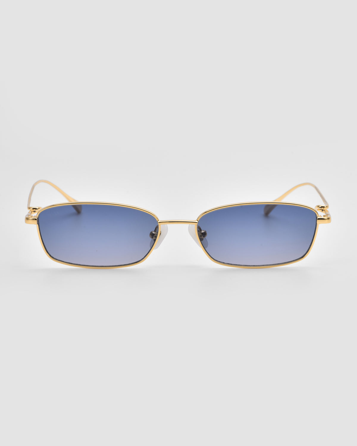 Ozanne II by For Art’s Sake®: gold-framed rectangular sunglasses with blue-tinted lenses and sculptural temples, shown on a plain light gray background.