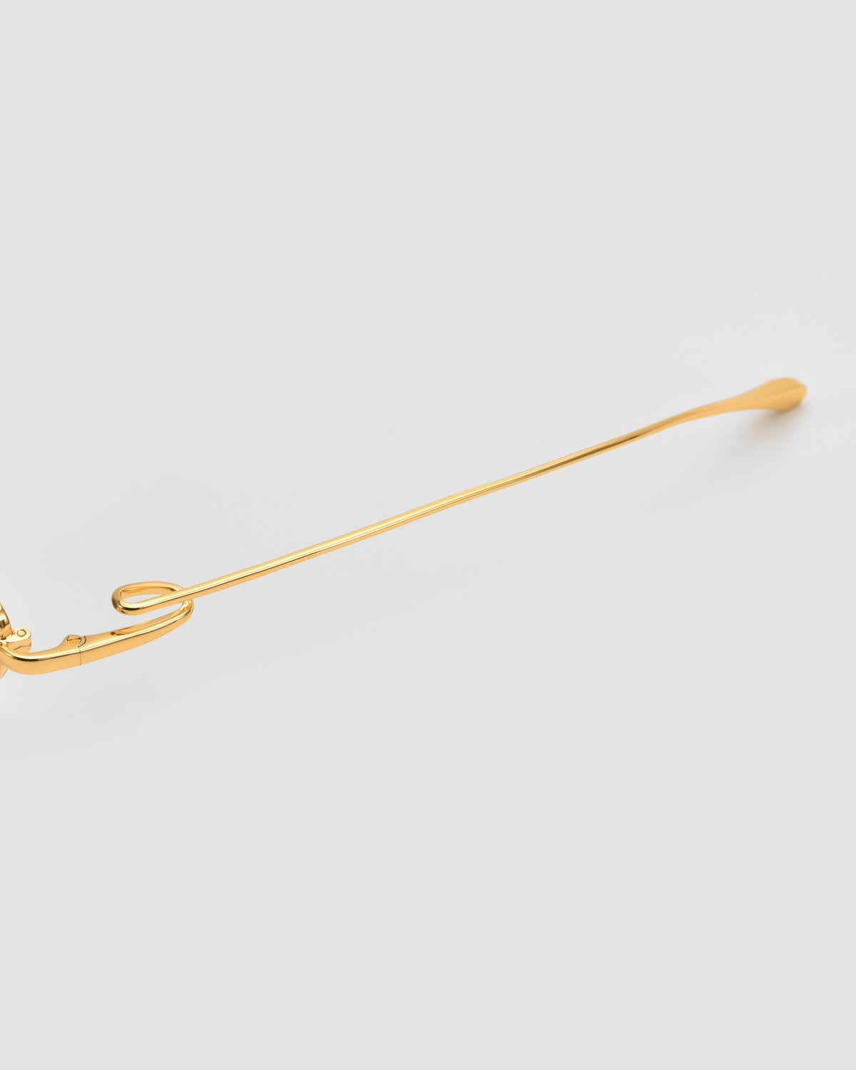 A close-up of the gold metal temple on Ozanne II by For Art’s Sake®, featuring a sculptural looped design inspired by jewelry, set against a plain white background.