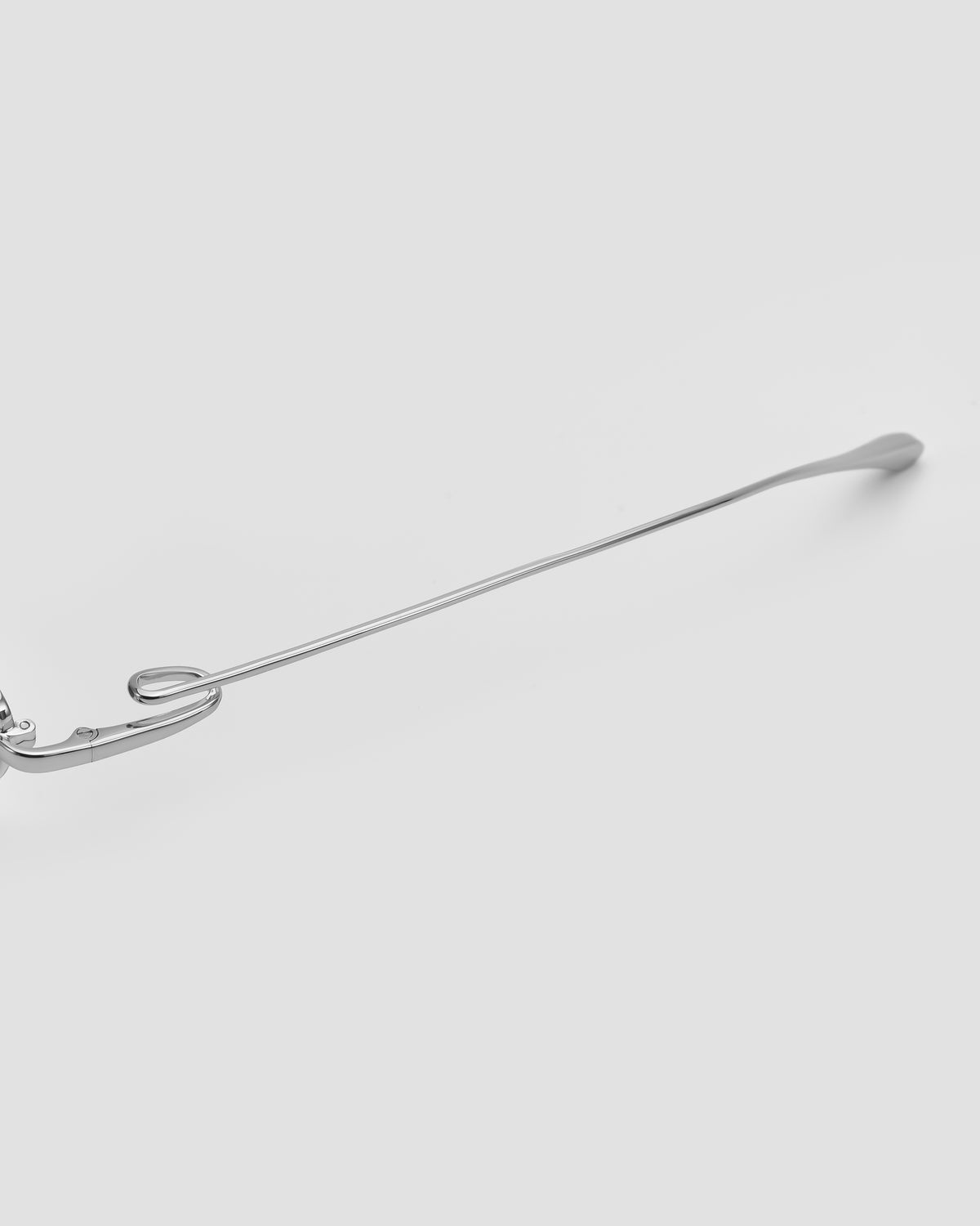 A close-up of the Ozanne II by For Art’s Sake® reveals its sleek, minimalistic silver temple arm and jewellery-inspired eyewear design on a plain light gray background.