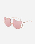 The For Art's Sake® Teddy sunglasses have pink, bear-shaped lenses and thin gold frames on a white background. The temples of the glasses have a slight angular design where they meet the lenses. Featuring UV protection, these stylish shades also come with adjustable nosepads for added comfort and fit.