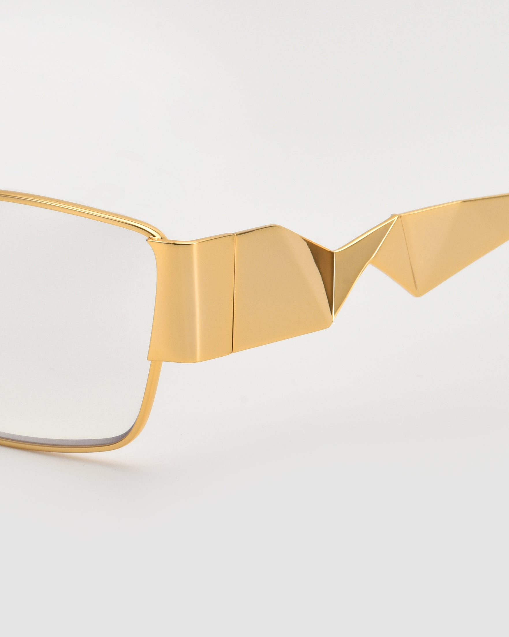 Close-up of For Art&#39;s Sake® Origami eyeglasses, featuring geometric gold accents and pleated temples, set against a white background—highlighting their sculptural, origami-inspired design.