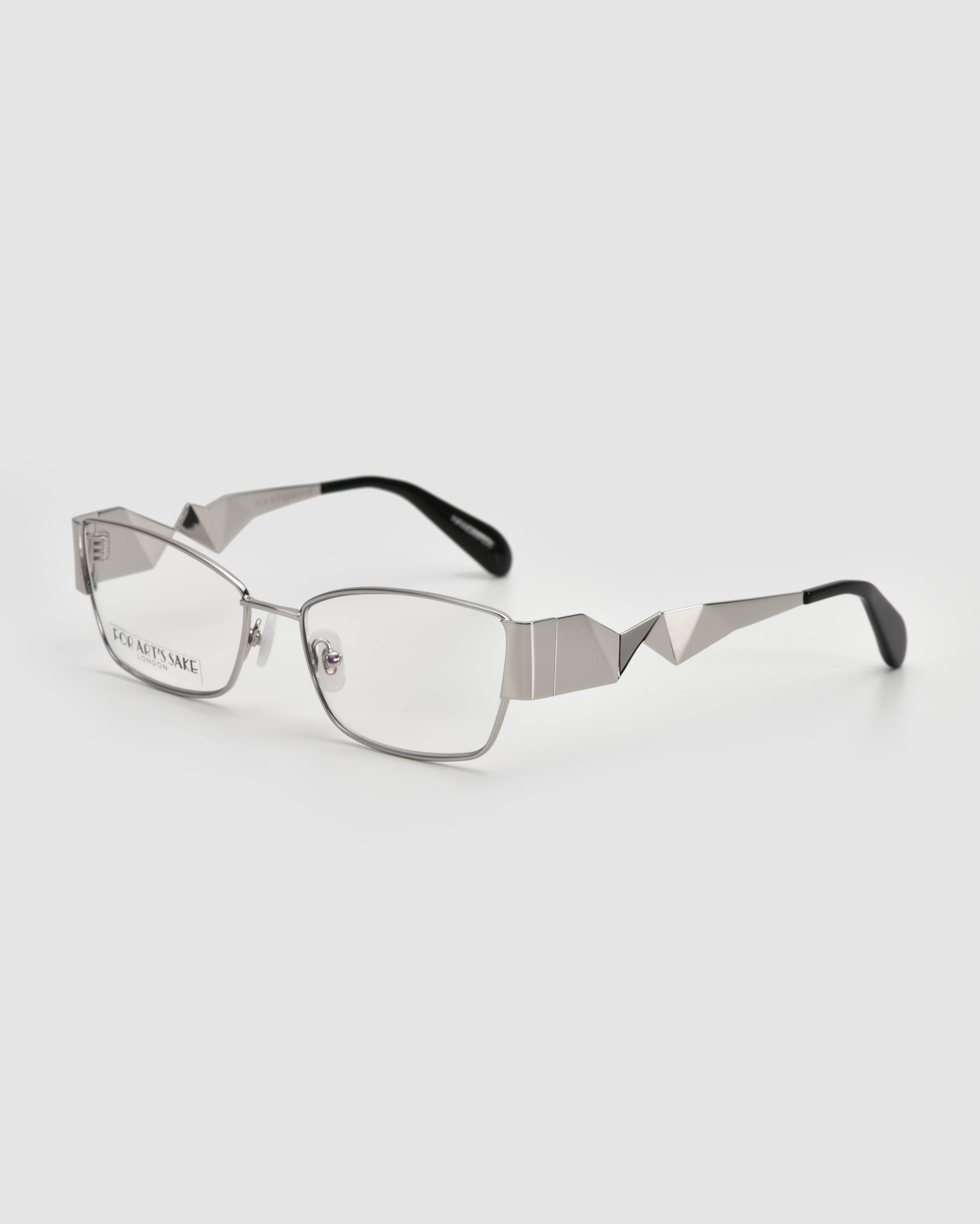 Origami by For Art's Sake®: rectangular silver metal eyeglasses featuring a soft-square silhouette, geometric angular arm details, and black tips, shown on a plain white background.
