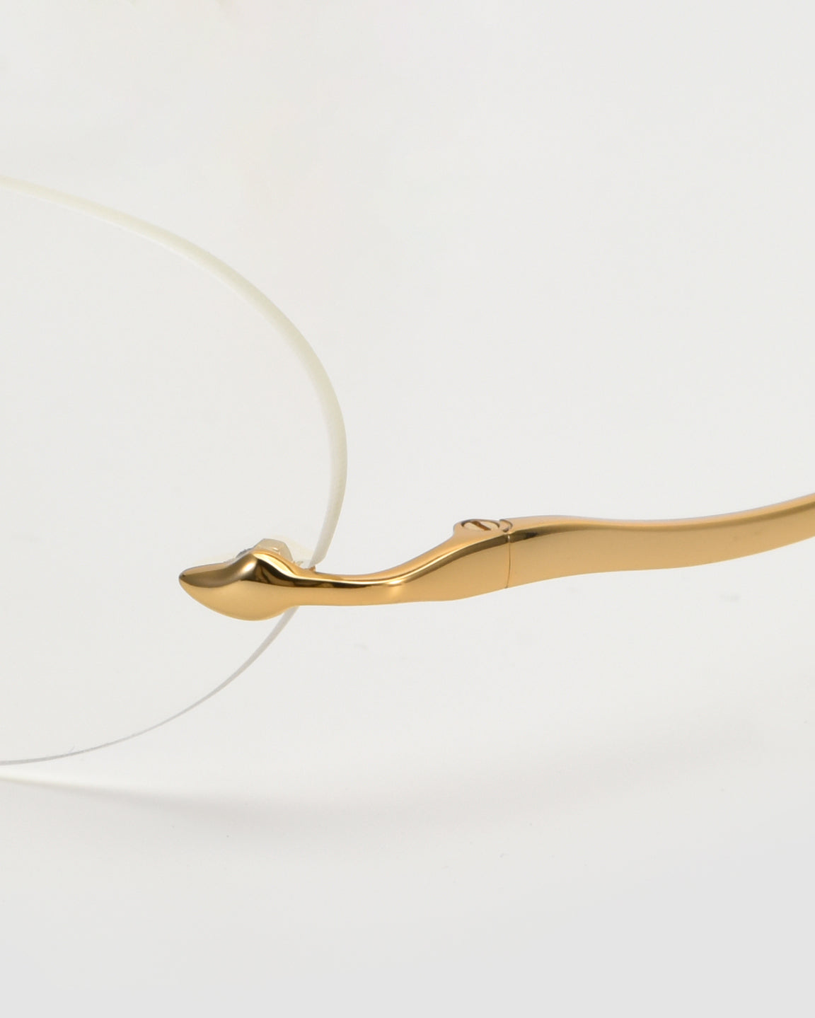 A close-up of the For Art&#39;s Sake® Waver gold minimalist eyeglass frame with rimless lenses, showcasing the elegant curved temple and seamless arm-to-lens connection against a white background.