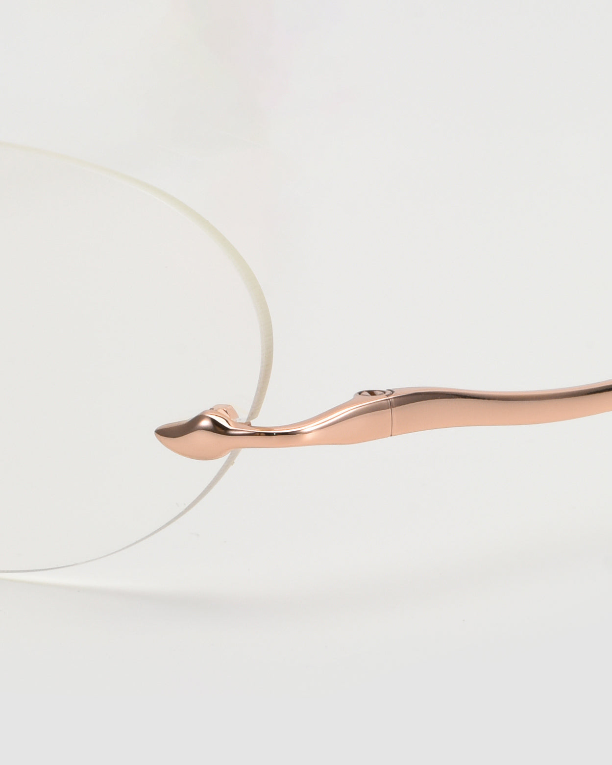 Close-up of For Art&#39;s Sake® Waver eyewear with a rose gold curved metal temple and clear lens, highlighting the minimalist, lightweight frames against a clean white background.