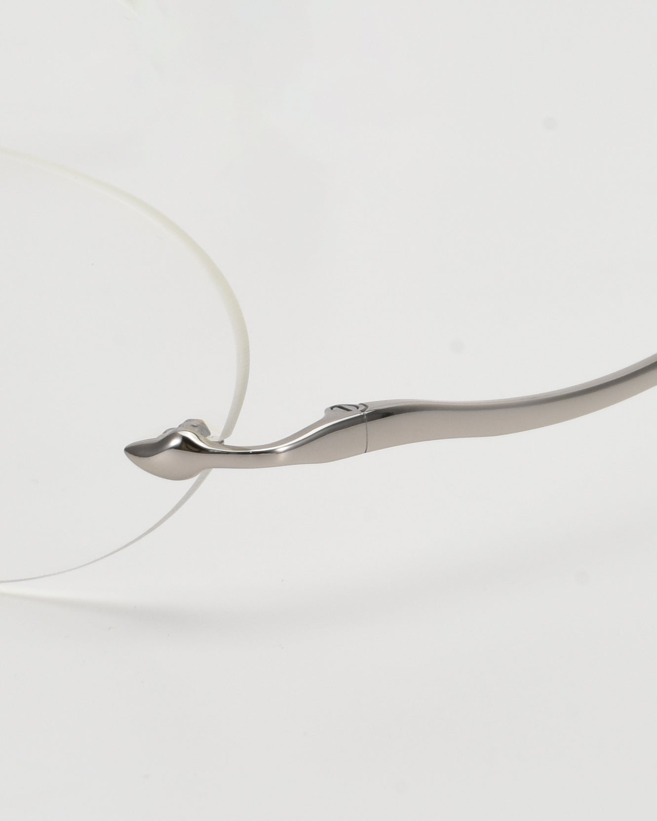 Close-up of For Art&#39;s Sake® Waver, featuring lightweight oval rimless glasses and a distinctively curved metallic silver temple arm, set against a white background.