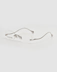 The For Art's Sake® Waver features oval rimless eyeglasses with thin silver metal arms and clear lenses on a white background—ideal for minimalism lovers.