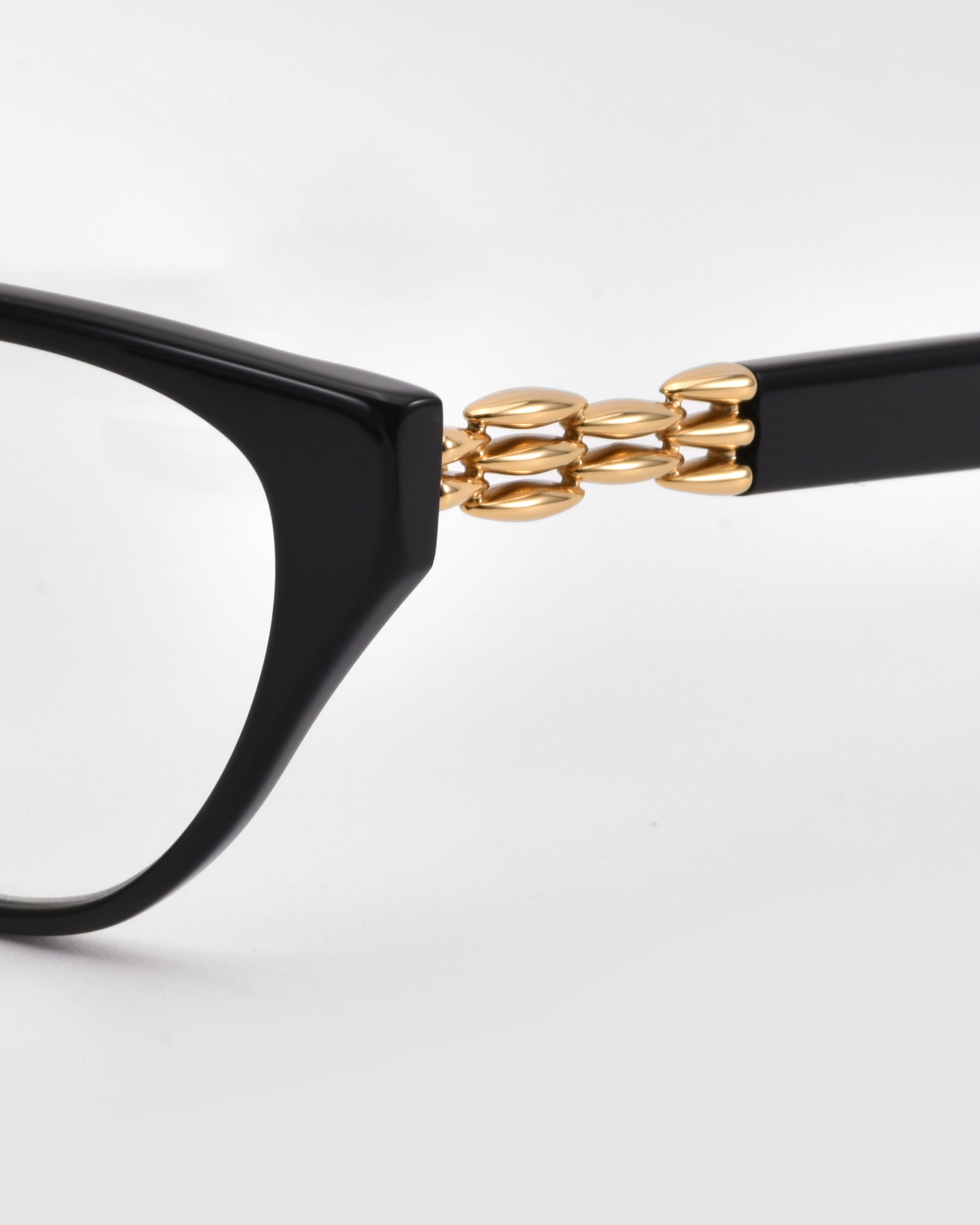 Close-up of The Act black cat-eye sunglasses by For Art&#39;s Sake®, showcasing a sculptural 3D weaved metal chain-link detail from the front frame to the temple, set against a plain white background.