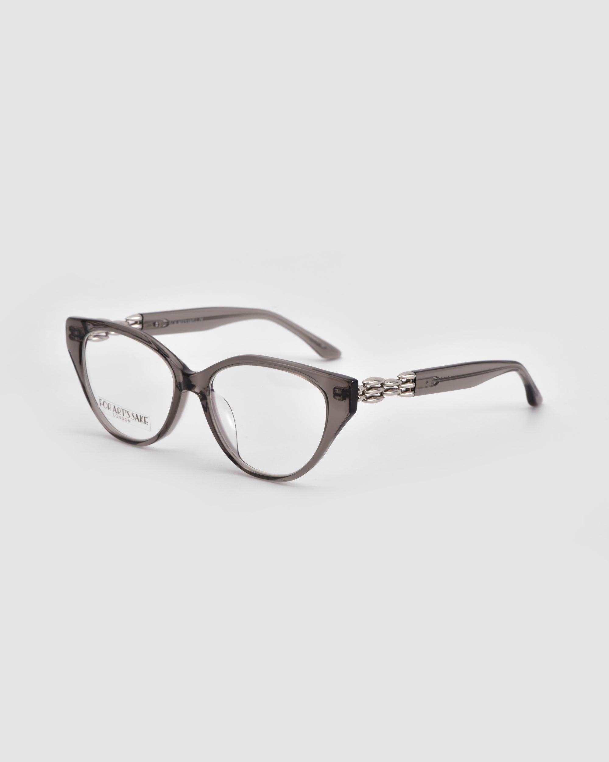 The Act by For Art's Sake® are translucent gray, round eyeglasses with lightweight frames and decorative metal temple accents, shown on a light gray background.