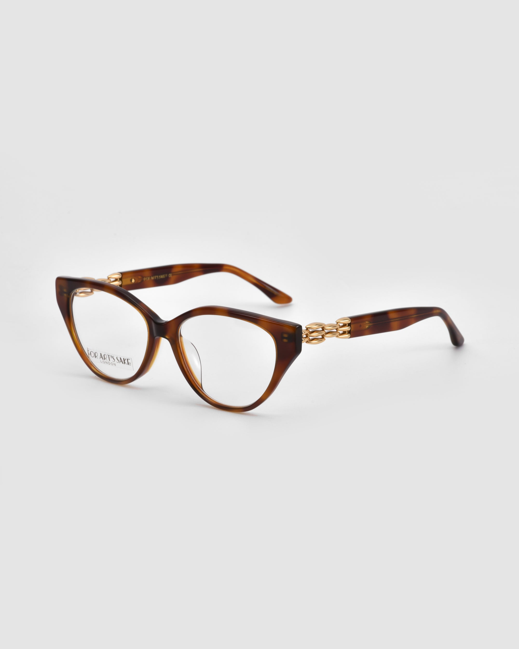The Act by For Art's Sake® are brown tortoiseshell eyeglasses with oval lenses, gold accents on the arms, and a lightweight frame, shown against a plain white background.