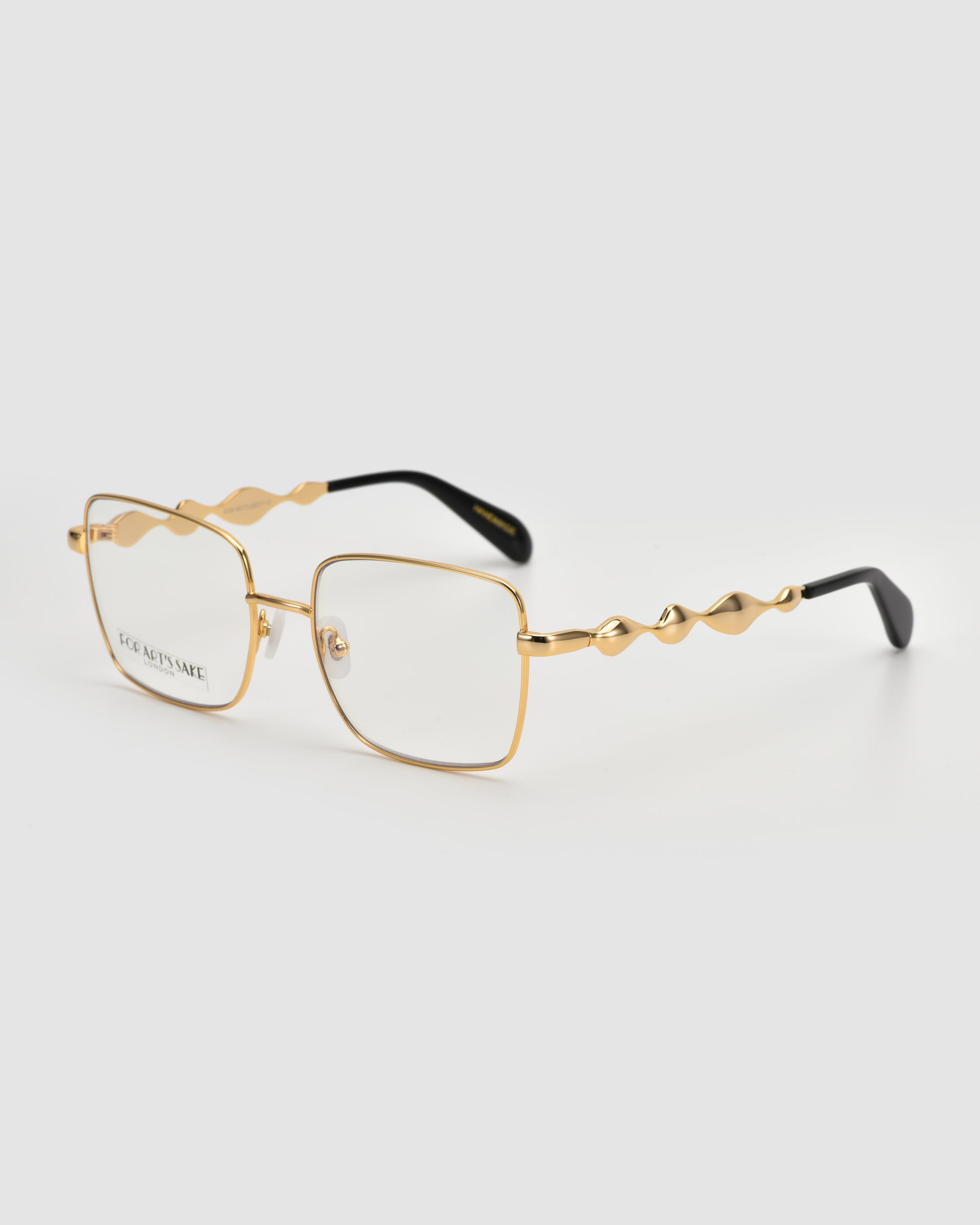 For Art's Sake® Fluid: Gold metal frame glasses with a soft square shape and wavy 3D fluid design temple arms with black tips, shown on a light gray background.