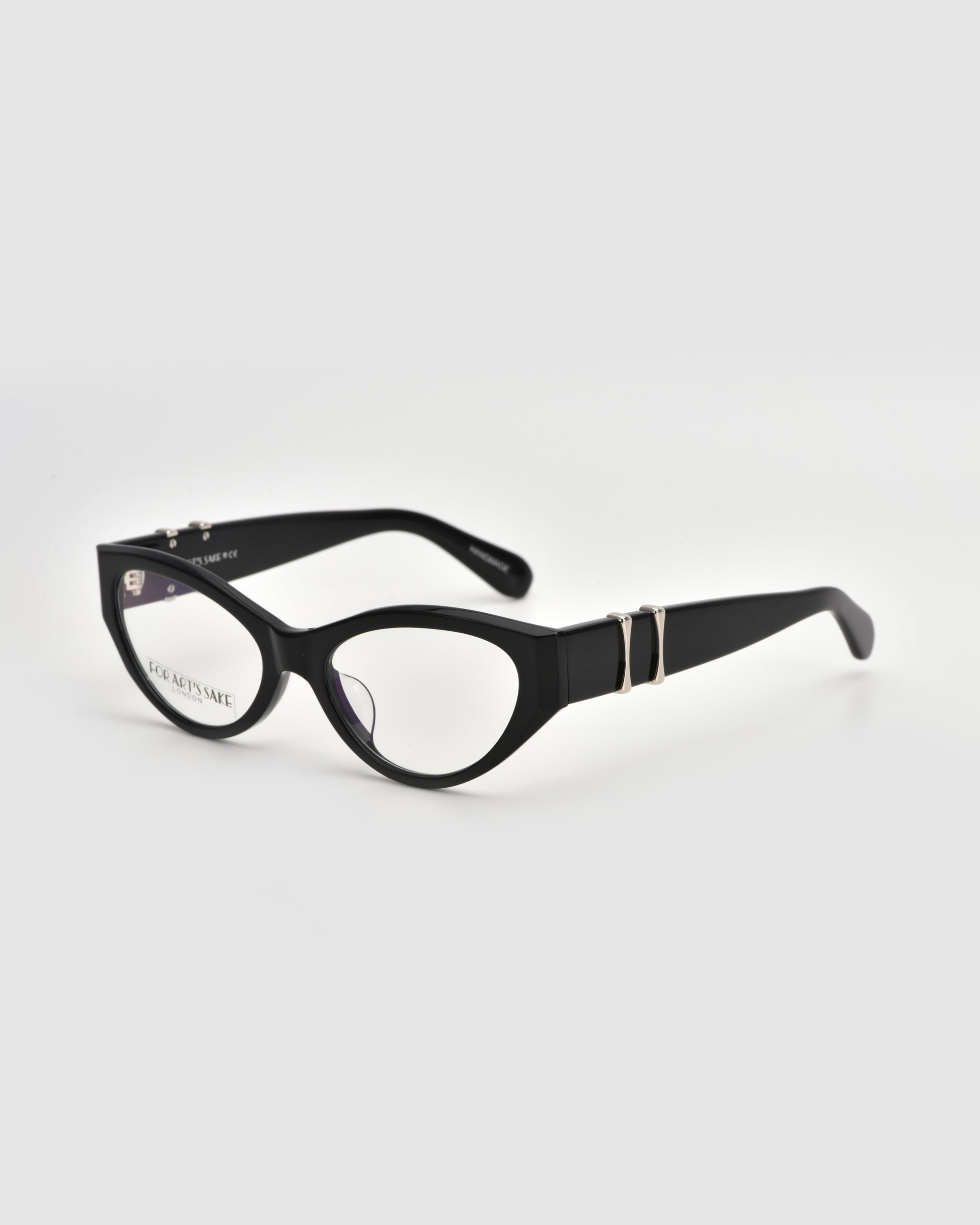 The Halo(X) by For Art's Sake® are black cat-eye eyeglasses with a sculptural acetate frame and decorative silver temple accents, shown on a white background.