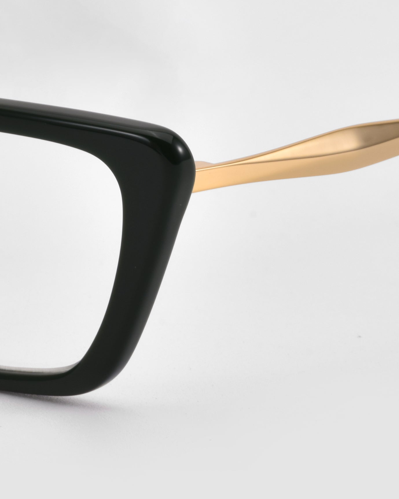 Close-up of Harmony(X) sunglasses by For Art&#39;s Sake® featuring a thick black rectangular frame and a sleek gold temple arm, set against a plain white background.