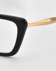 Close-up of Harmony(X) sunglasses by For Art's Sake® featuring a thick black rectangular frame and a sleek gold temple arm, set against a plain white background.