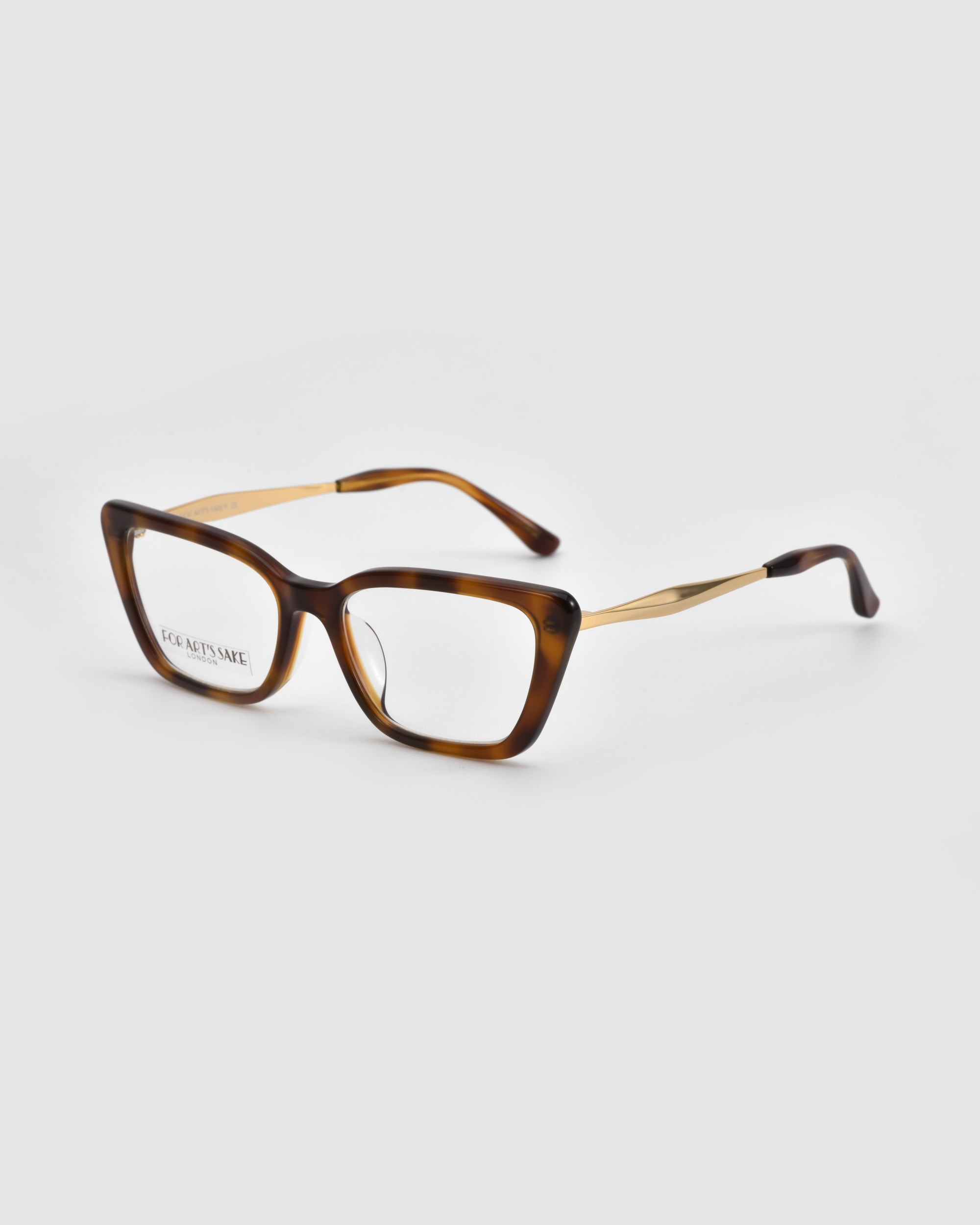 The Harmony(X) eyeglasses by For Art's Sake® feature a tortoiseshell pattern, boxy silhouette, rectangular lenses, and gold sculptural temples, displayed on a light gray background.