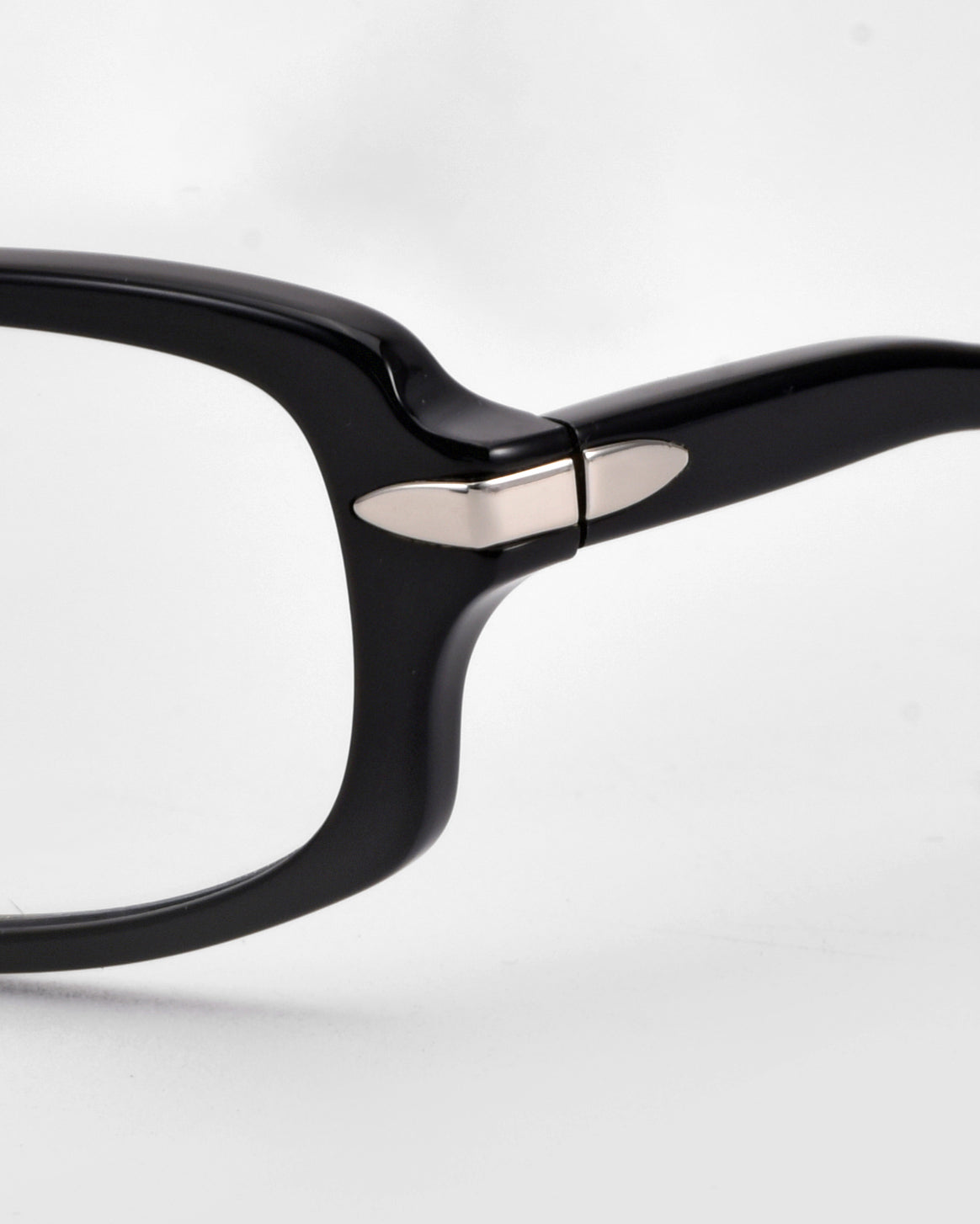 Close-up of the hinge and arm of the For Art&#39;s Sake® Motion II black eyeglass frames, featuring a small silver metal accent on the hinge and curved acetate temples, set against a plain white background.