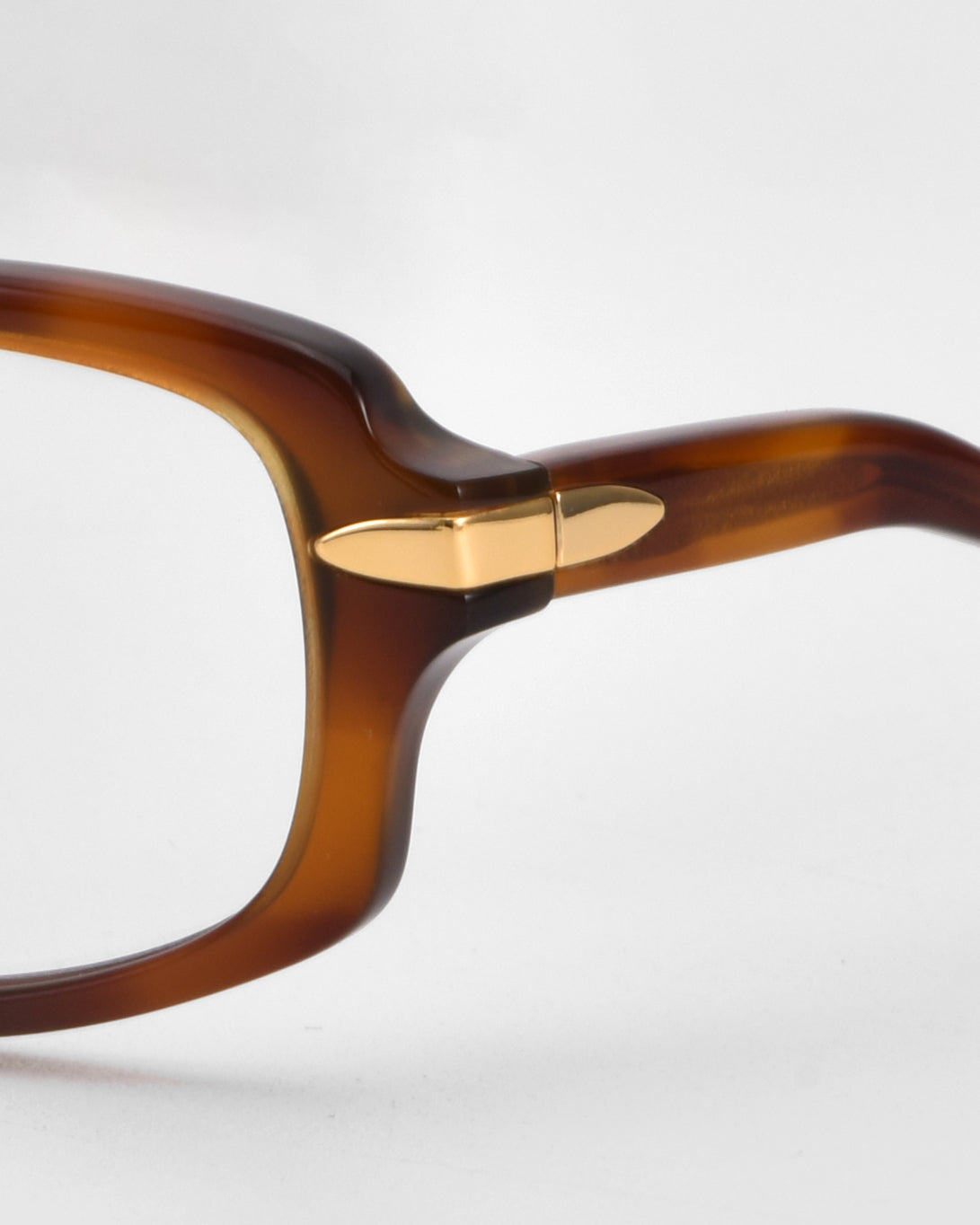 Close-up of the right side of For Art&#39;s Sake® Motion II brown boxy rectangular eyeglass frames, featuring a gold metal hinge accent and curved acetate temples, set against a plain white background.