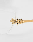 Close-up of For Art's Sake® Ida eyeglasses featuring lightweight frames and gold metal temples with three small flower accents. Set against a plain, light background, the elegant floral optical design is beautifully highlighted.