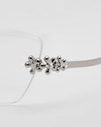 Close-up of For Art's Sake® Ida cat-eye glasses with a metallic, abstract floral design on the temple hinge, set against a white background.