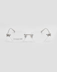 Ida by For Art's Sake® are rimless cat-eye glasses with silver metal arms, clear lenses, jeweled floral accents on the upper corners, and "FOR ART'S SAKE" on the left lens. Set against a light gray background.
