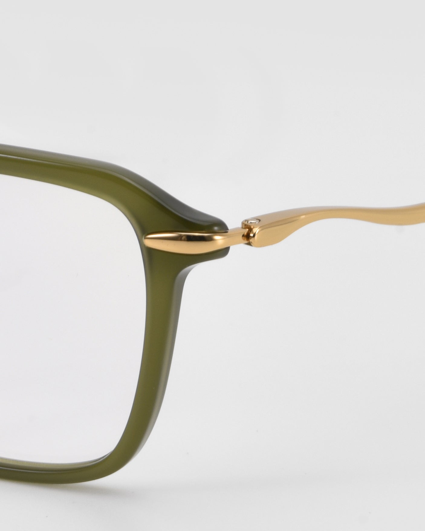 Close-up of the Claudia eyeglass frame by For Art's Sake® with an olive green rectangular acetate and metal front and sleek gold sculpted temples, set against a plain light background.