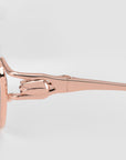 Close-up of the hinge and arm of For Art's Sake® Anita eyeglasses in metallic rose gold, highlighting their geometric metal design and lightweight comfort against a plain light gray background.