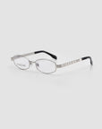 The Iris by For Art's Sake® is a pair of silver metal eyeglasses with oval lenses, thin striped arms, and black temple tips, showcased on a plain light gray background.