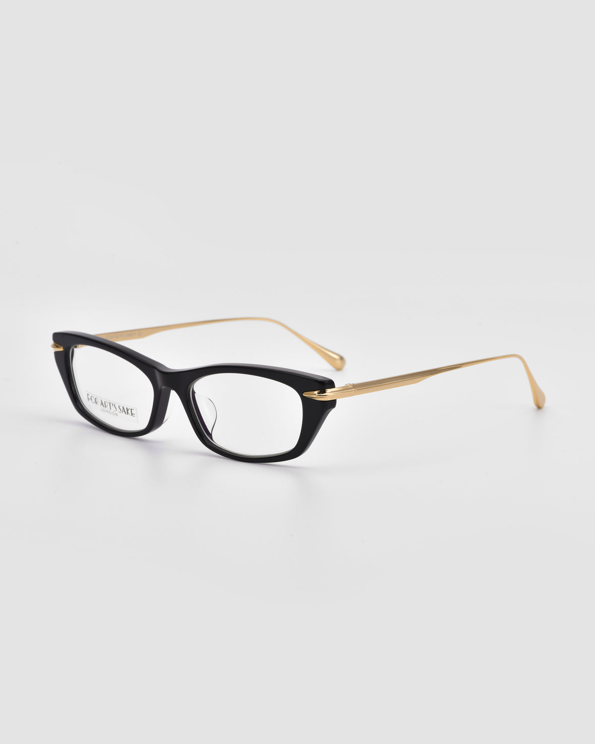 Suri I by For Art’s Sake®: black rectangular optical frames with gold metal temple detailing, shown on a plain white background.