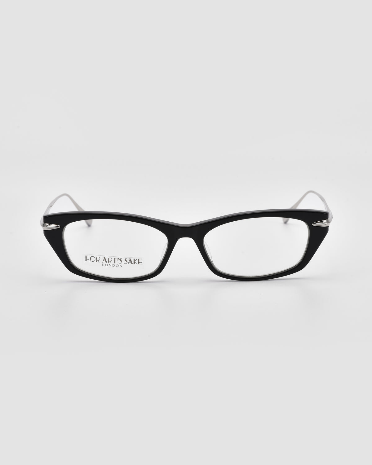 Suri I by For Art’s Sake®: Black-framed optical frames with clear lenses and subtle metal temple detailing, viewed from the front on a white background. “FOR ART’S SAKE.” is printed on the inside of the left lens.