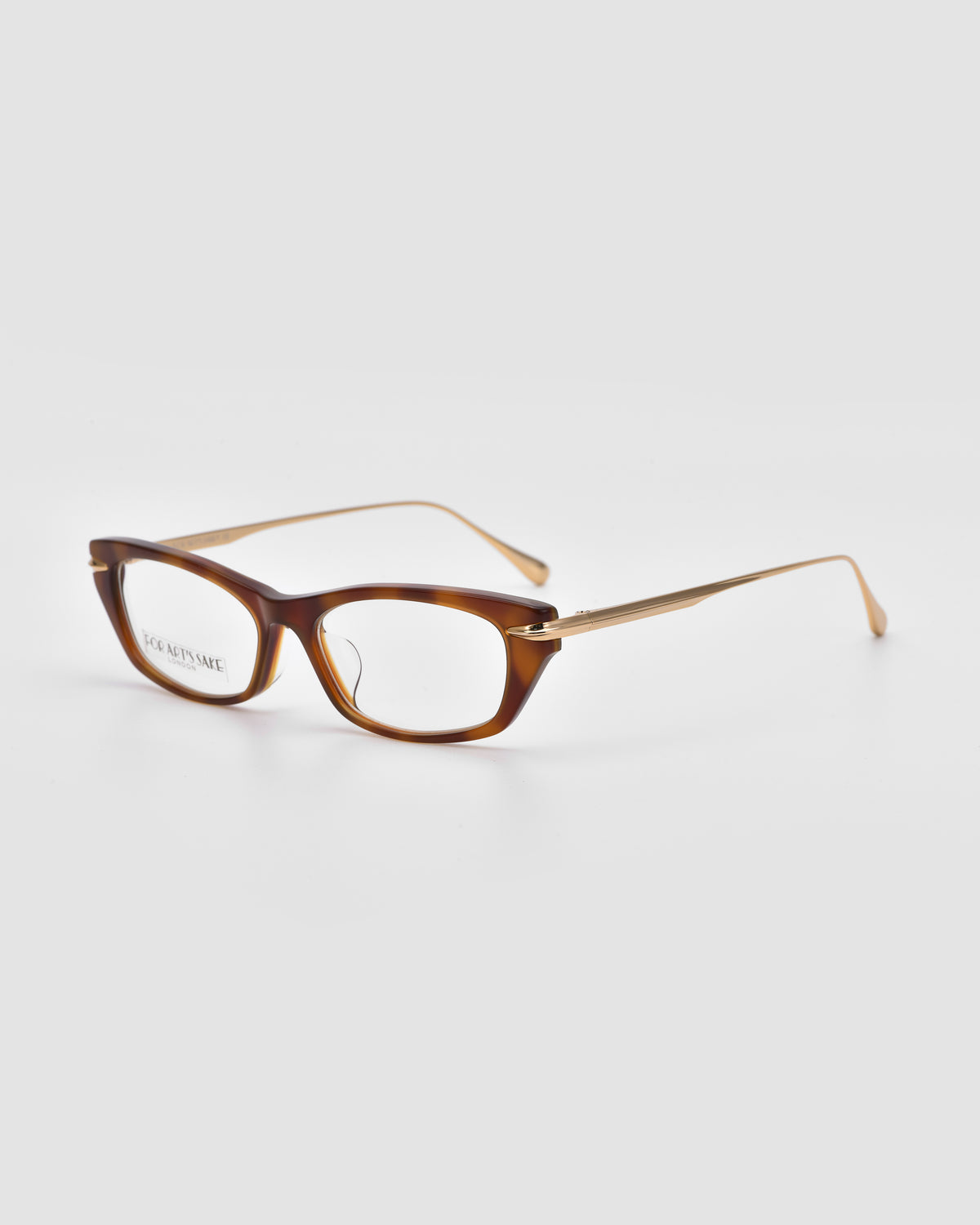 For Art’s Sake® Suri I: Brown acetate optical frames with rectangular lenses and thin temples, shown on a light gray background. The left lens bears a faint inscription, emphasizing their glossy finish.