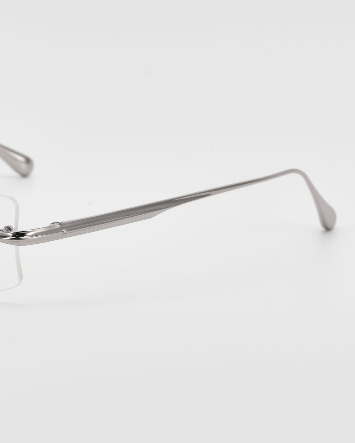 A close-up of the side arm of Suri II by For Art’s Sake®, highlighting the hinge and part of the lens against a white background.