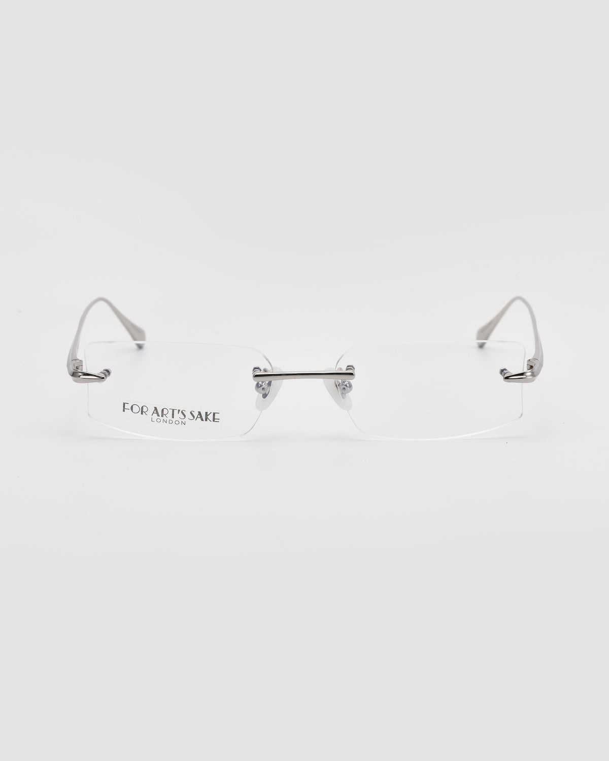 Suri II by For Art’s Sake®: Rimless glasses with silver metal temples, jade nose pads, and a clear bridge; “For Art’s Sake London” on the left lens, shown on a white background.