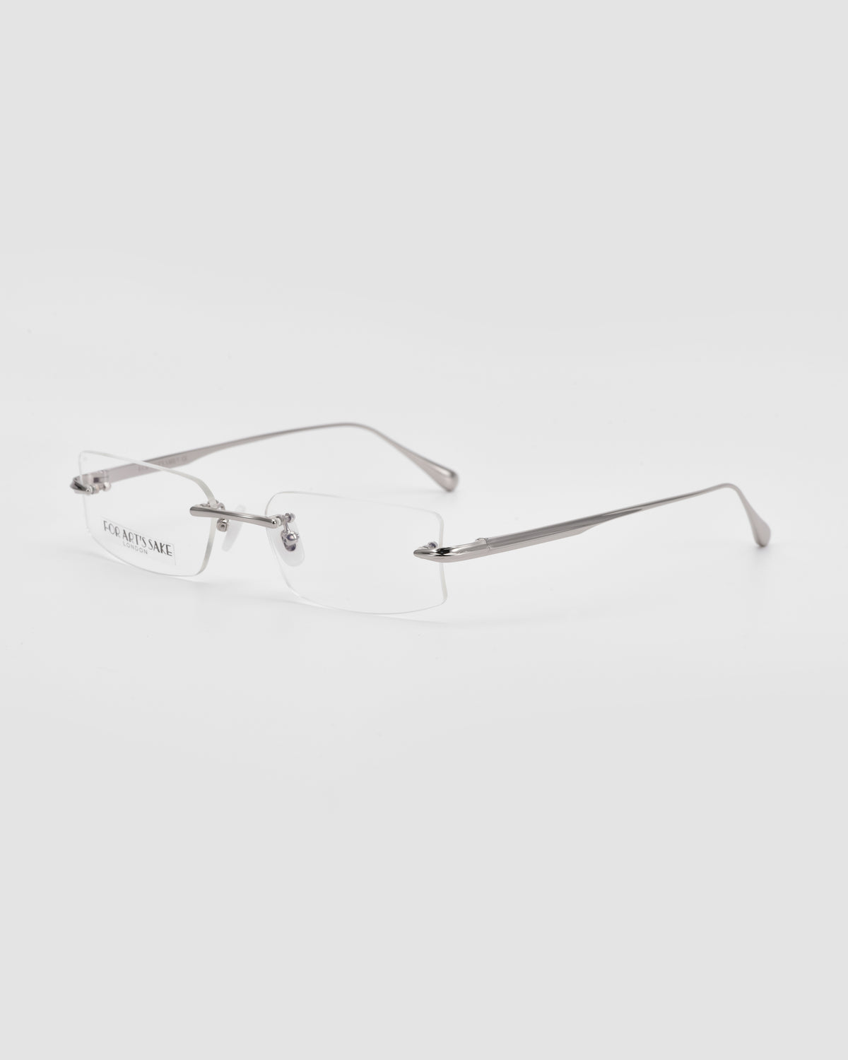 Suri II by For Art’s Sake®: rimless glasses featuring thin silver metal arms, jade nose pads, and clear rectangular lenses, shown on a plain white background.