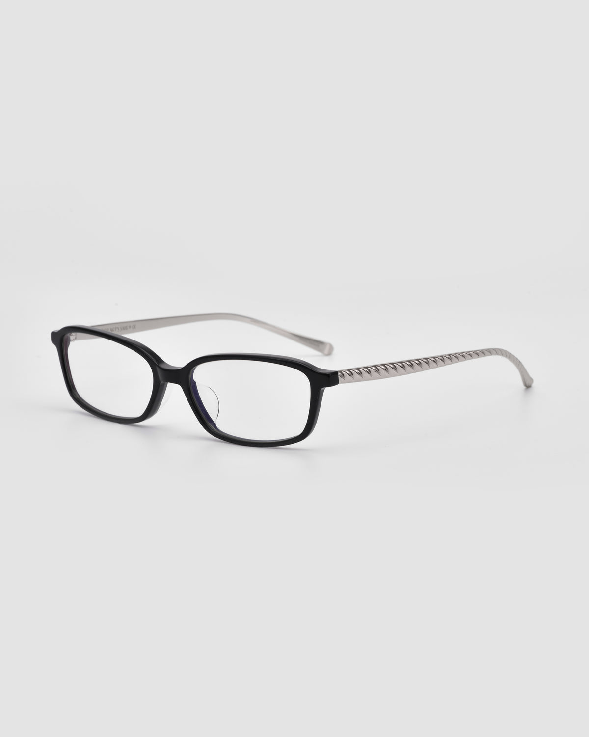 The Lumi I by For Art’s Sake® are black rectangular optical frames with white patterned arms and sleek metal temples, shown on a plain light background.