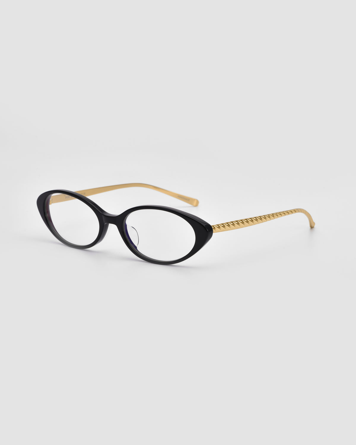 Lumi II by For Art’s Sake® features black cat-eye acetate frames and gold textured temples—striking statement eyewear set against a light gray background.