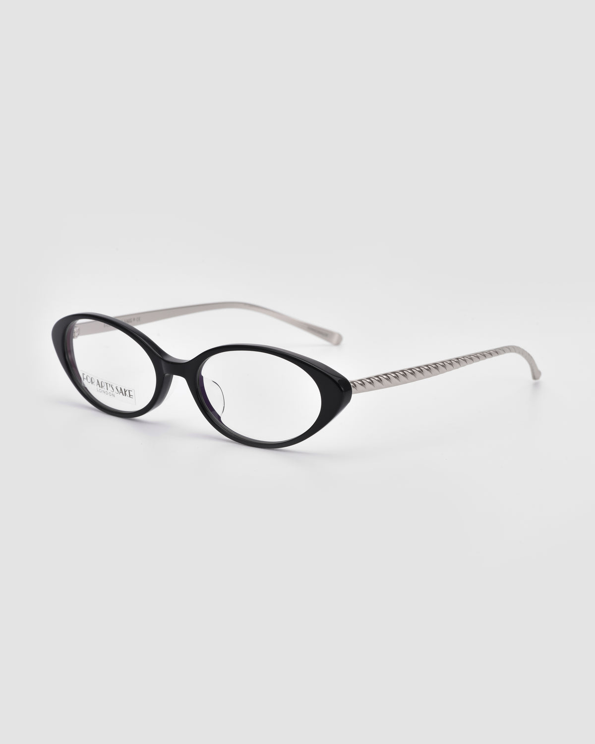 Lumi II by For Art’s Sake®: black cat-eye acetate optical frames with clear lenses and silver patterned temple arms, shown on a light gray background.