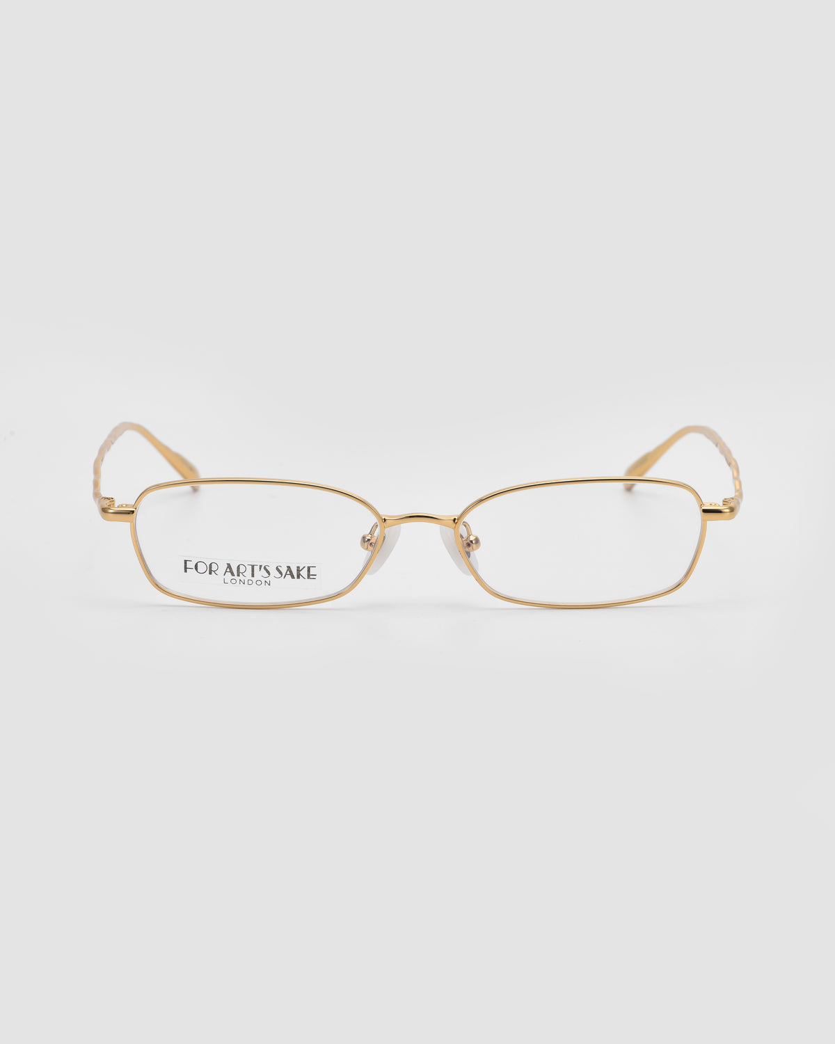 A pair of Suree I rectangular gold optical frames by For Art’s Sake®, featuring thin rims and clear lenses. “For Arts Sake London” is printed on the left lens, displayed on a plain white background.